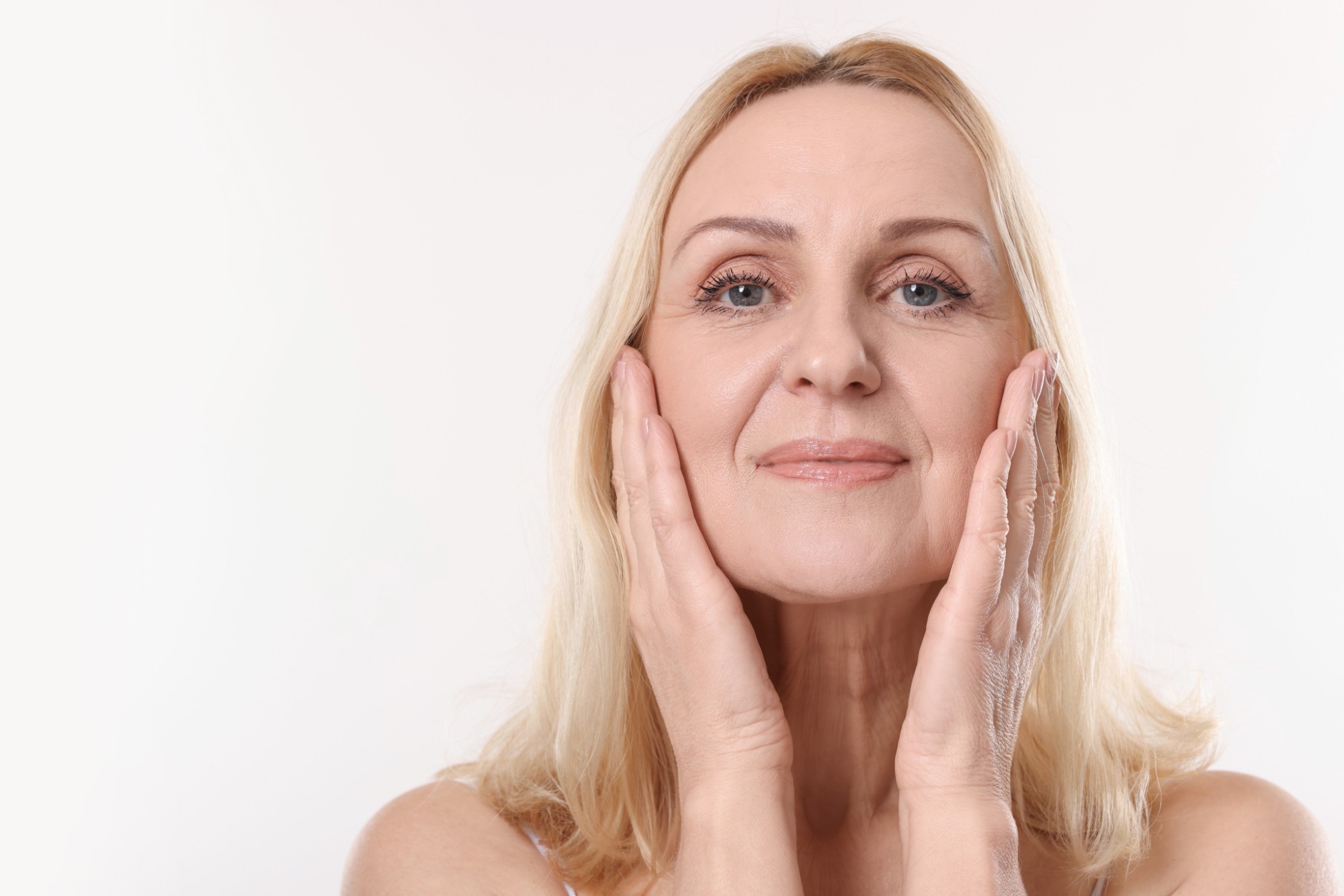 Mujer rubia con las manos en las mejillas y mirada descansada